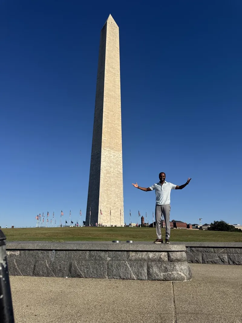 Michael standing arms out in front of the Washington Monument